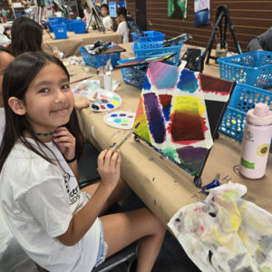 Image of art camper painting canvas creatively with gradient colors during art camp at Cheers N Paint studio.