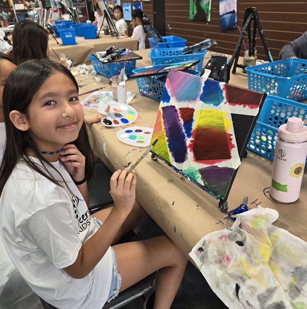 Image of art camper painting canvas creatively with gradient colors during art camp at Cheers N Paint studio.