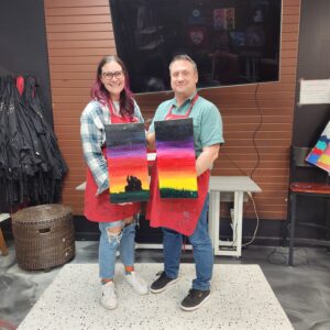Couple Holding Painted Canvases Together In Cheers N Paint Art Studio In Cary, Nc