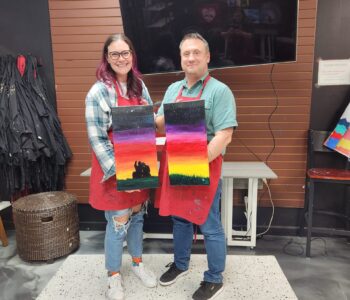 Couple holding painted canvases together in Cheers N Paint Art Studio in Cary, NC